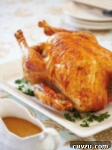 An old-fashioned roast turkey on a white platter, with gravy in a boat beside it.