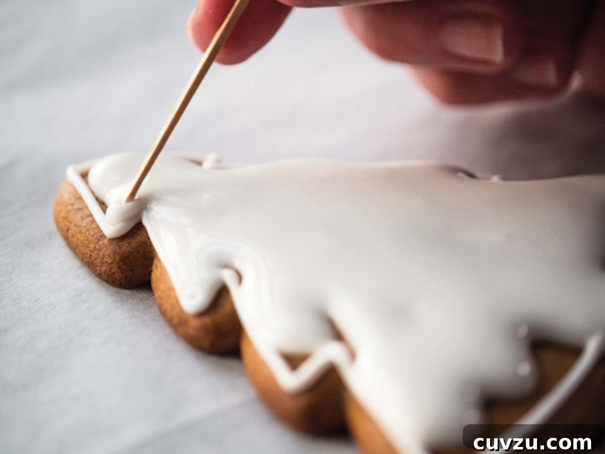 The Art of Royal Icing Decoration 4 A Christmas tree-shaped cookie being filled with smooth, green royal icing for a solid base.
