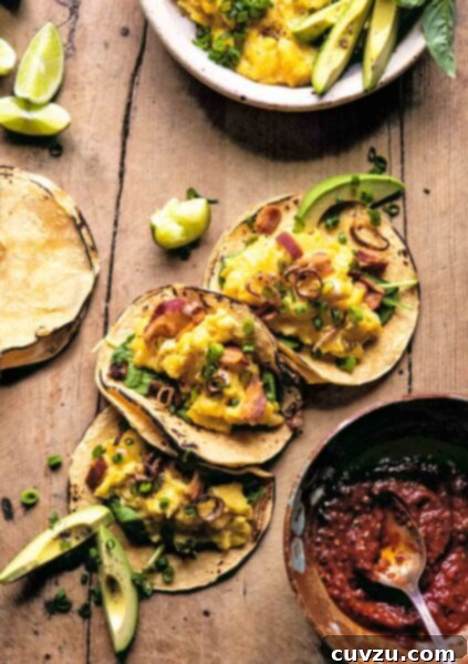 Three avocado breakfast tacos with eggs, bacon, shallots, and chives with a bowl of salsa on the side. A delightful presentation of a satisfying morning meal.