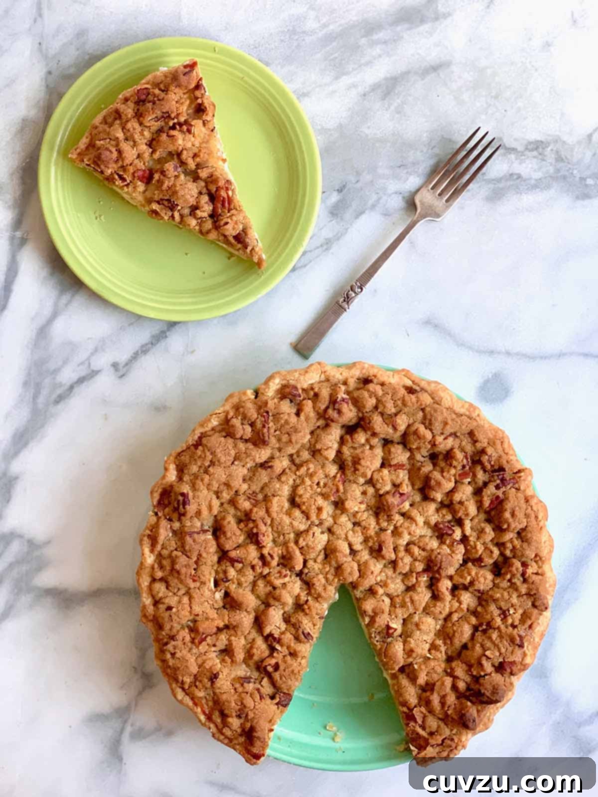 Velvet Apple Pie 3 A sour cream apple pie with one slice cut out and place on a green plate and a fork resting beside it.