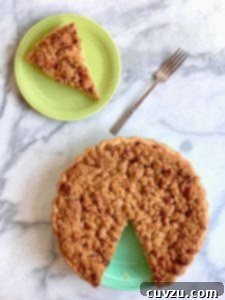 Velvet Apple Pie 4 A sour cream apple pie with one slice cut out and place on a green plate and a fork resting beside it.