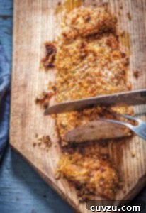 Golden Panko Pork Tenderloin with Aromatic Rosemary 3 A panko-crusted pork tenderloin with rosemary being sliced on a wooden cutting board, with a focus on the crispy crust.