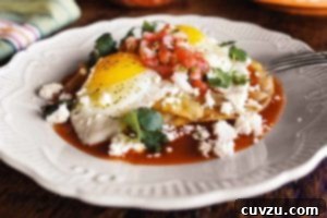 A white plate topped with huevos rancheros - crispy tortilla, fried eggs, fresh salsa, and Cotija cheese.