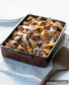 A rectangular casserole dish brimming with baked polenta, sausage, and melted cheese, ready to serve.