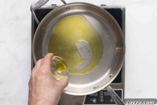 Blistered Skillet Broccolini 11 A person pouring olive oil into a skillet.