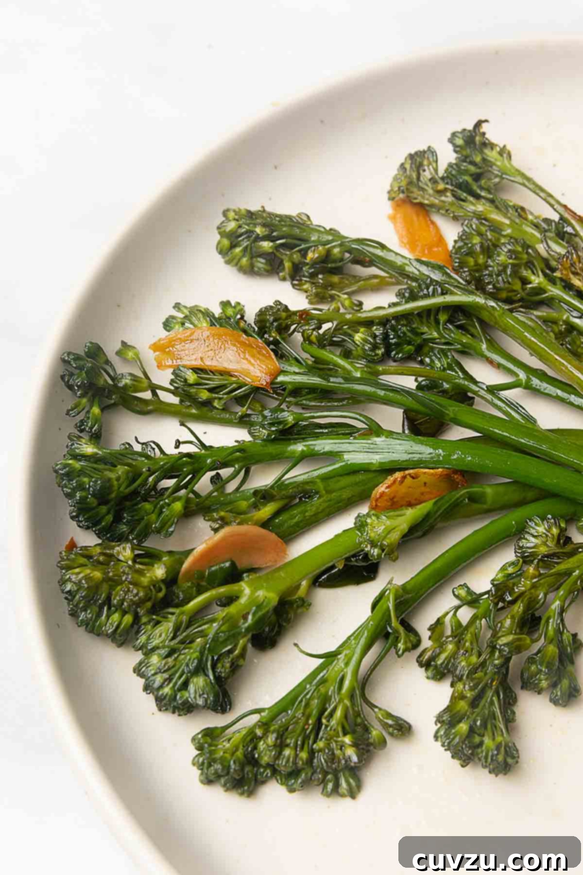 Blistered Skillet Broccolini 8 Seared broccolini and slices of browned garlic on a plate.