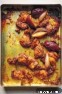 Flavorful Chicken Shawarma Wraps 4 Cooked pieces of chicken shawarma and wedges of red onion on a rimmed baking sheet.