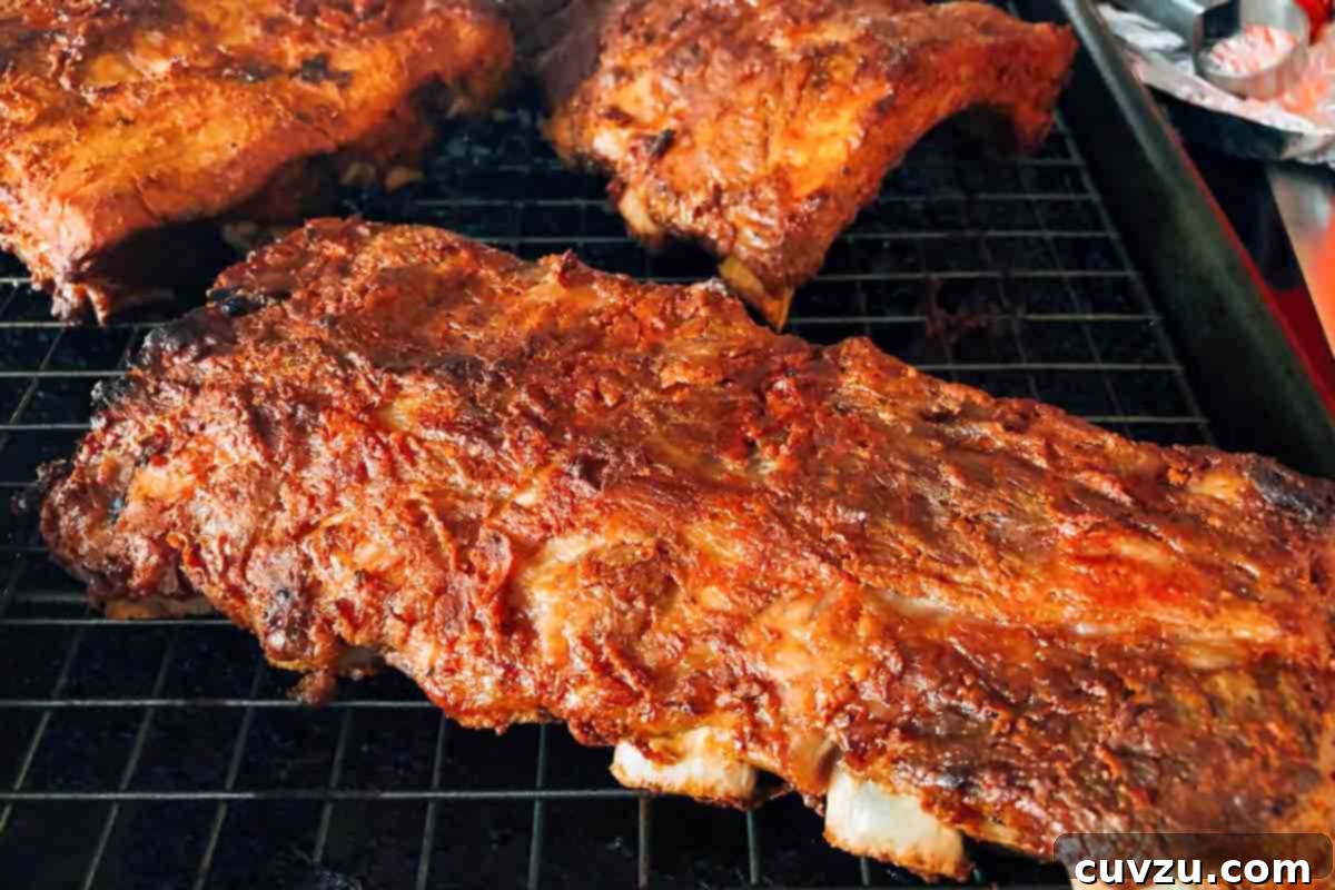 Four slabs of BBQ oven ribs on a rack inside a rimmed baking sheet, presented beautifully for serving.