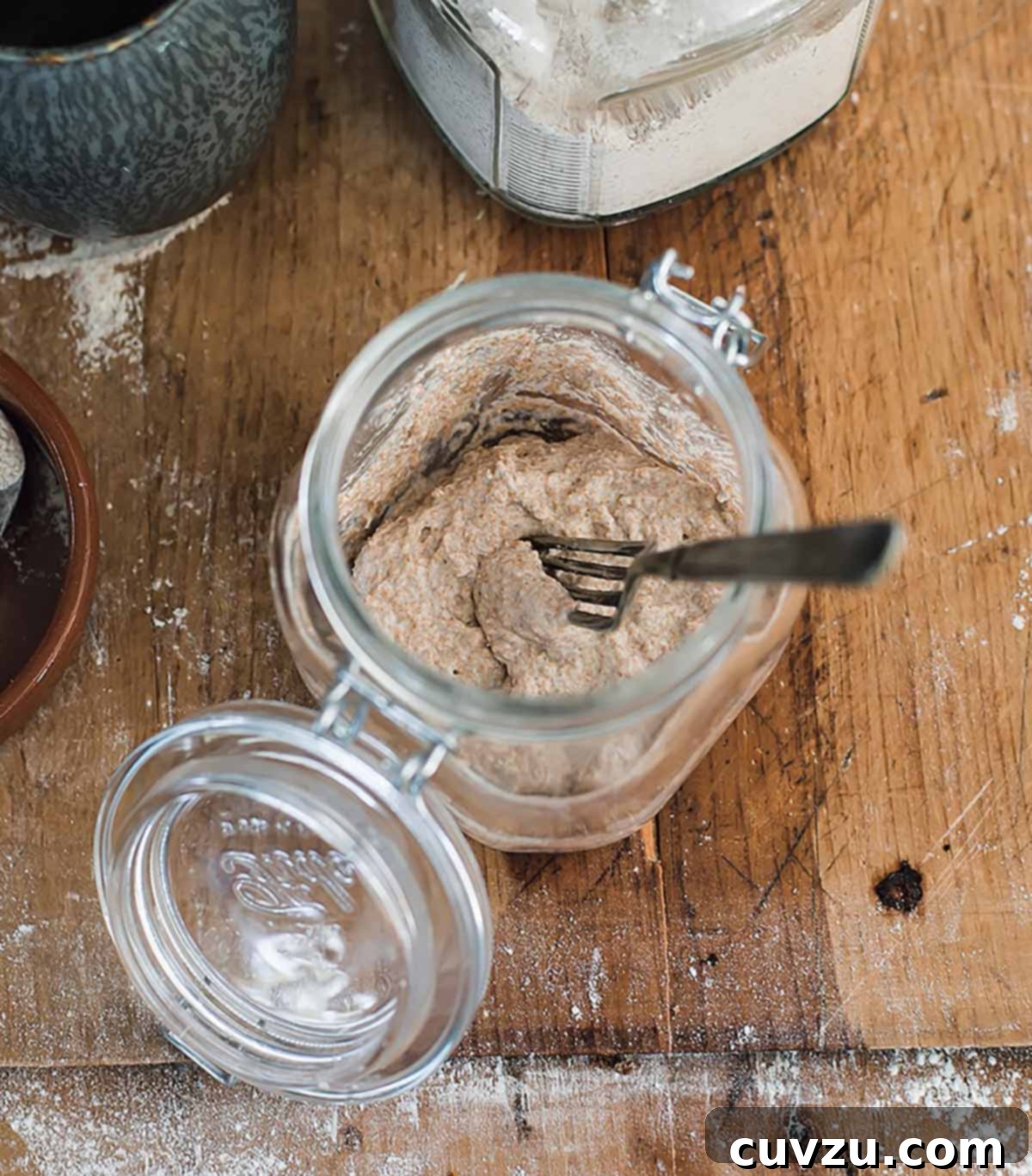 Crafting Your Sourdough Magic 3 Glass jar containing flour and water mixture with a fork, representing the initial step of making a sourdough starter.