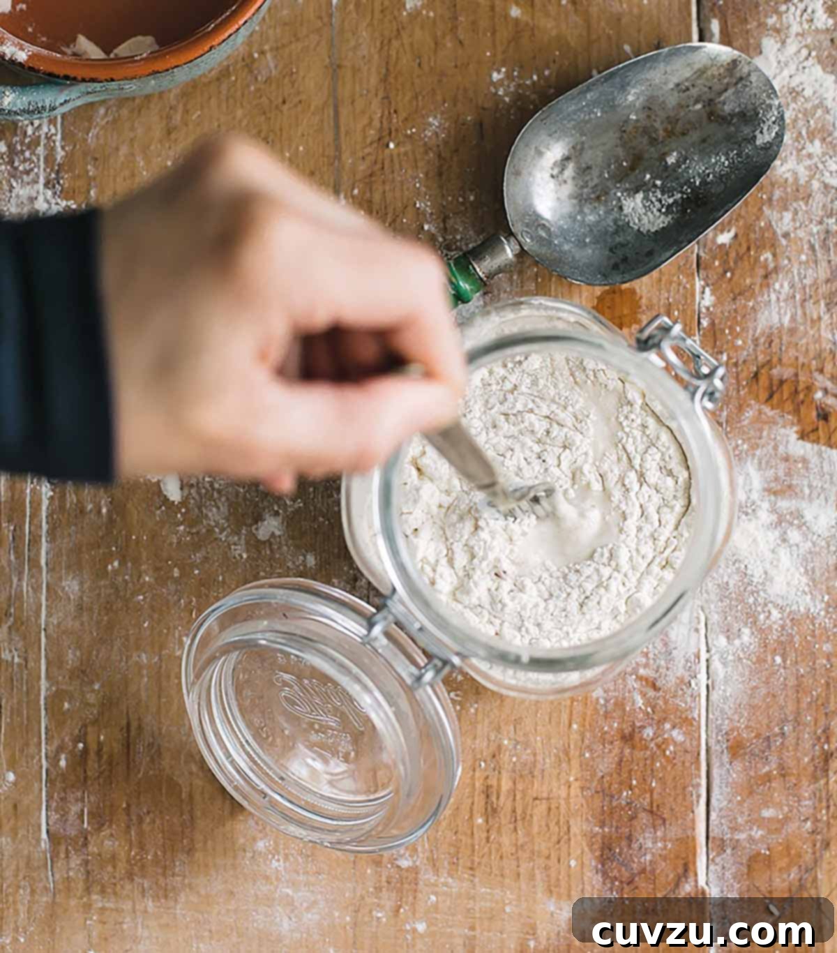 Crafting Your Sourdough Magic 5 A person stirring additional all-purpose flour into a sourdough starter, illustrating the first feeding.