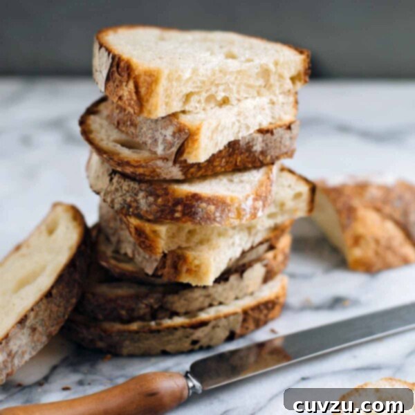 Halved slices of sourdough stacked on top of each other on a white and grey marble surface.
