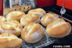 Papo Secos Portuguese Rolls 12 Several golden-brown, freshly baked Papo Secos cooling on a wire rack, showcasing their perfectly formed creases and crispy crusts.