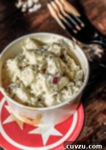 Crisp Apple Potato Salad 3 Potato Salad with Apples in a white serving bowl on top of a red and white star-patterned trivet.