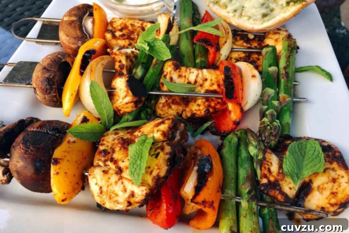 Three harissa vegetable skewers with halloumi on a white plate, served with fresh herbs.