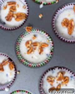 Unbaked blueberry pecan muffins in a muffin tin with pecans scattered on top.