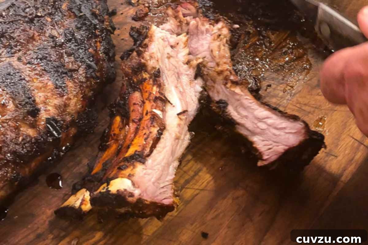 Sticky Vietnamese Glazed Ribs 4 A person cutting a rack of Vietnamese pork ribs on a wooden cutting board.