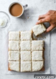 A frosted coconut sheet cake, expertly sliced into 12 squares, showcasing its inviting texture and rich, creamy topping.