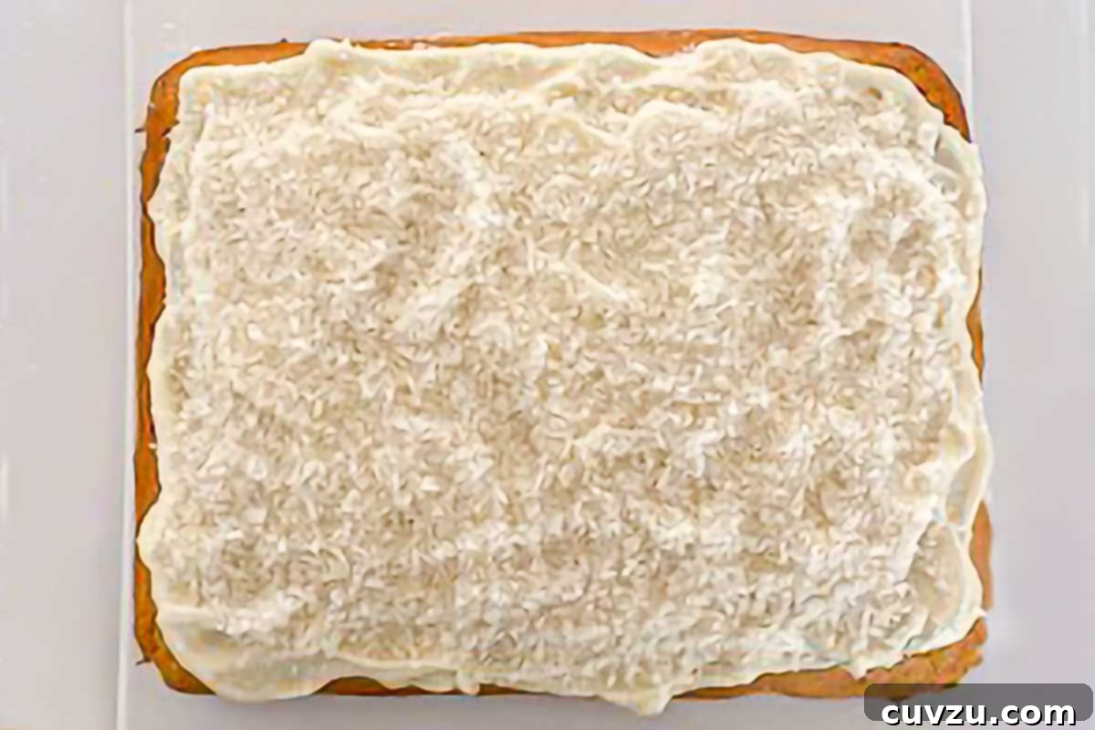 Heavenly Coconut Sheet Cake 6 A generously frosted coconut sheet cake, cut into serving squares, highlighting the appealing texture of the topping.