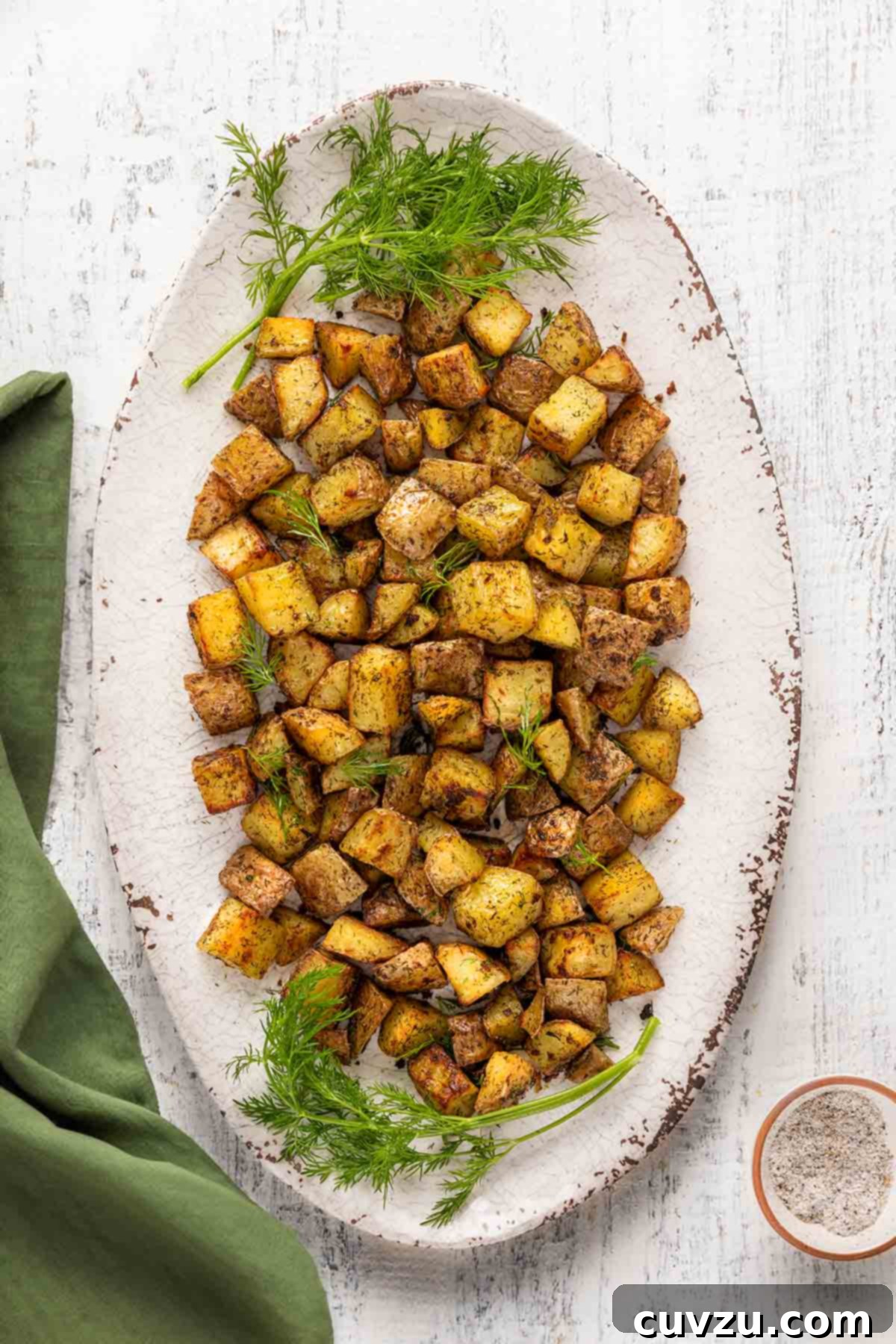 Golden Dill Roasted Potatoes 7 An oval platter filled with cubed roasted potatoes, garnished with fresh dill.