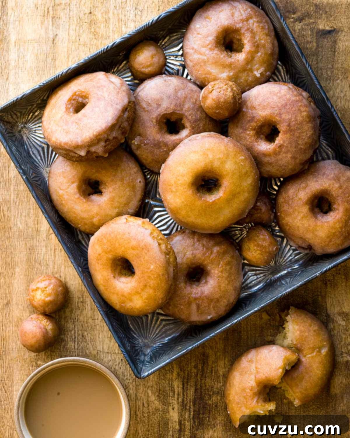 Autumn's Sweet Indulgences 9 A tray of golden-brown spiced cider doughnuts and doughnut holes, with one broken to reveal its fluffy interior, perfect for autumn mornings.