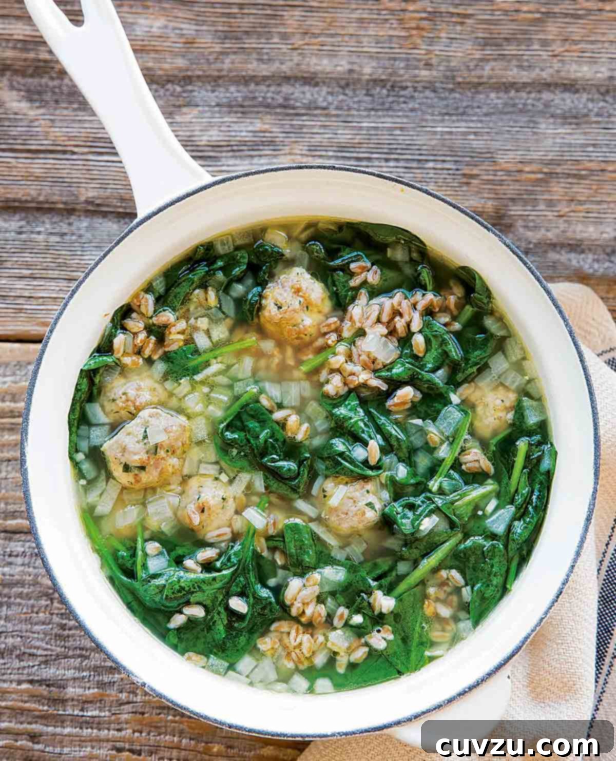 A white enamel pot filled with turkey meatball soup.