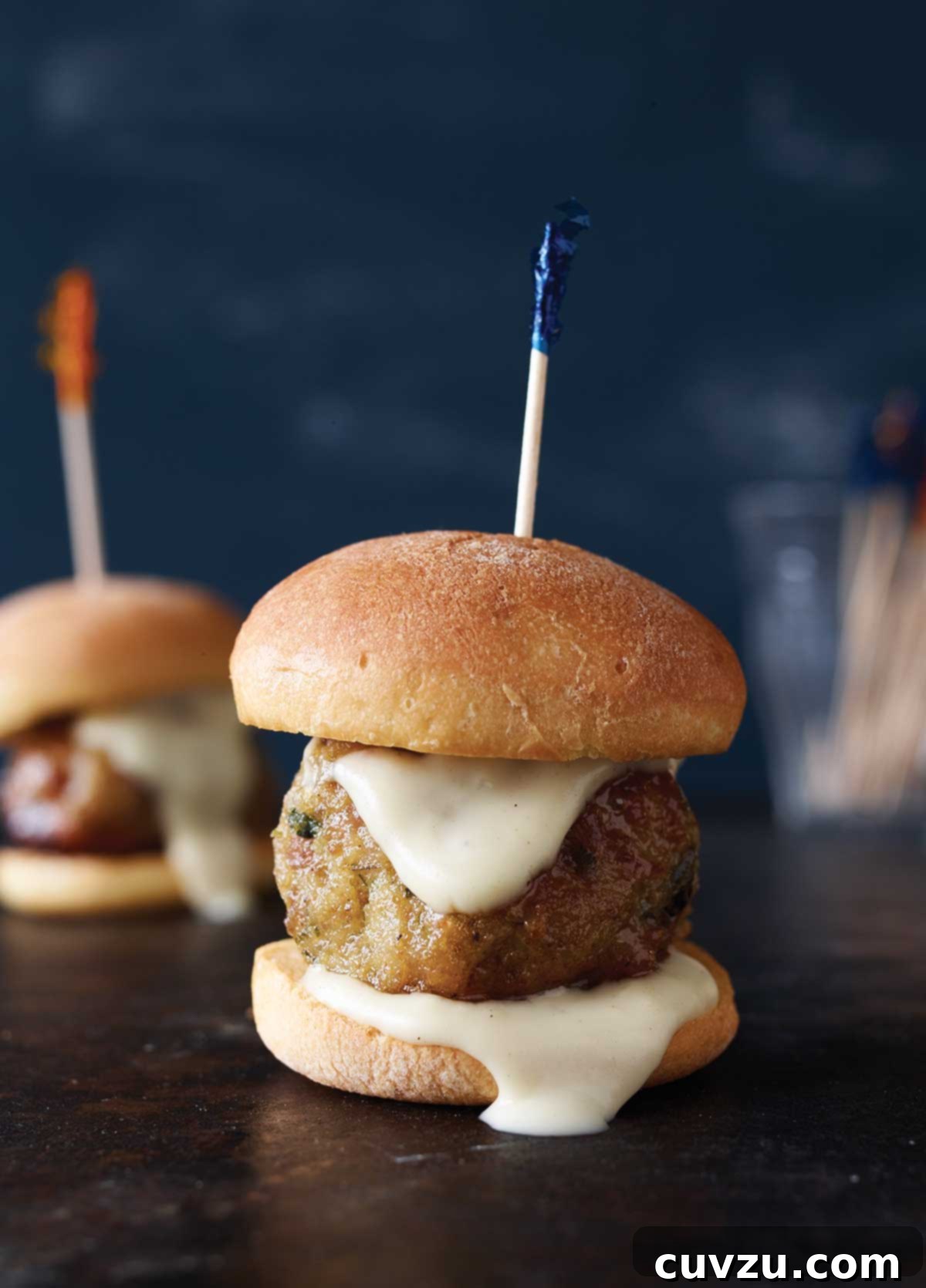 Two ground chicken meatballs on slider buns with a toothpick skewered through them.