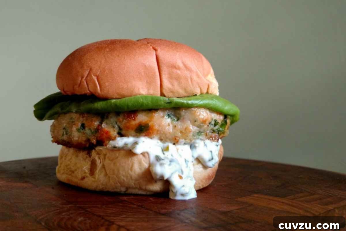 Gourmet Shrimp Burgers 6 A beautifully assembled shrimp burger with tartar sauce, topped with fresh lettuce, served on a wooden table, showcasing its delicious appeal.