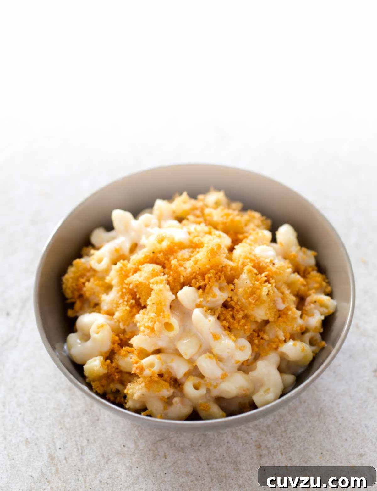 A grey ceramic bowl filled with baked mac and cheese with bread crumbs