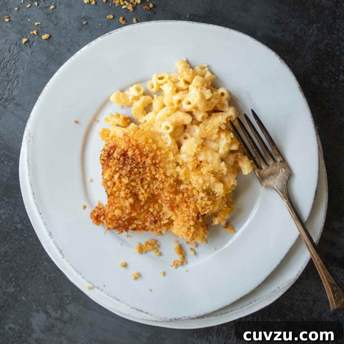 A plate of macaroni and cheese with a fork on the side.