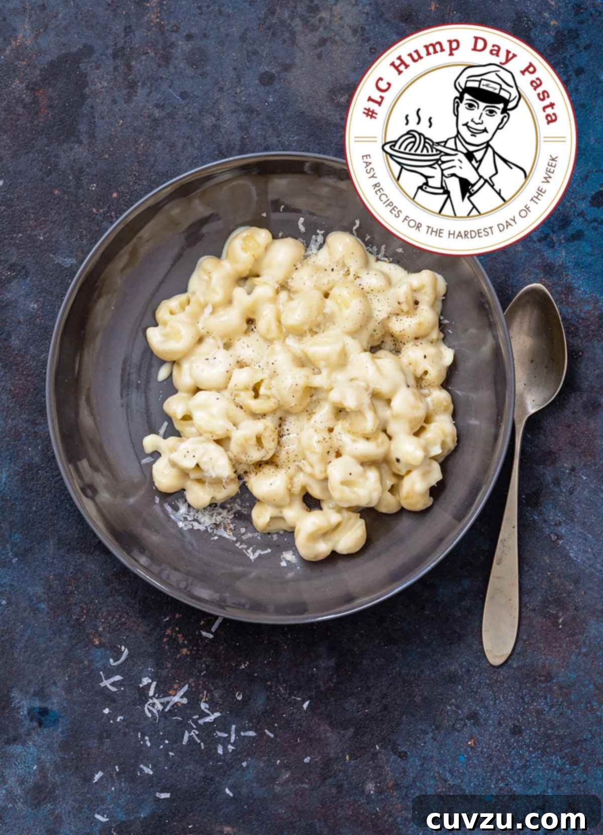 Skillet mac and cheese in a grey bowl with a spoon, garnished with extra shredded cheese.