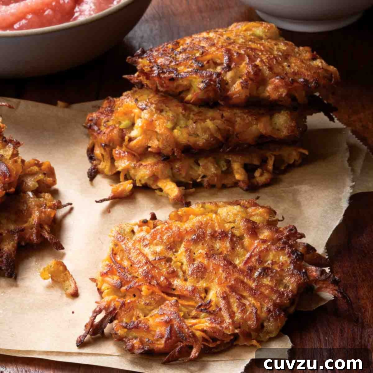 Light Up Your Table: 11 Hanukkah Recipes 5 Several sweet potato and apple latkes on a paper towel with a bowl of applesauce in the background.