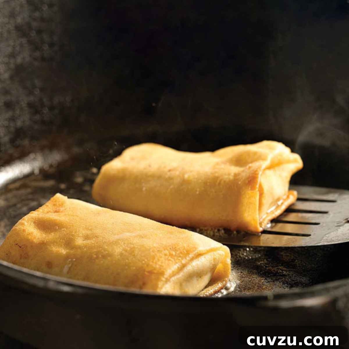 Light Up Your Table: 11 Hanukkah Recipes 10 Cheese blintzes in a cast-iron frying pan, one being lifted up by a metal spatula.