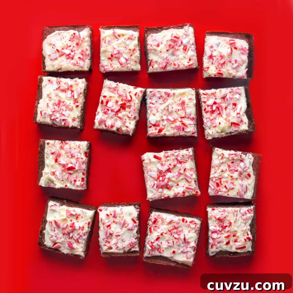 Fifteen brownies, frosted with white frosting and speckled with crushed peppermint candies.