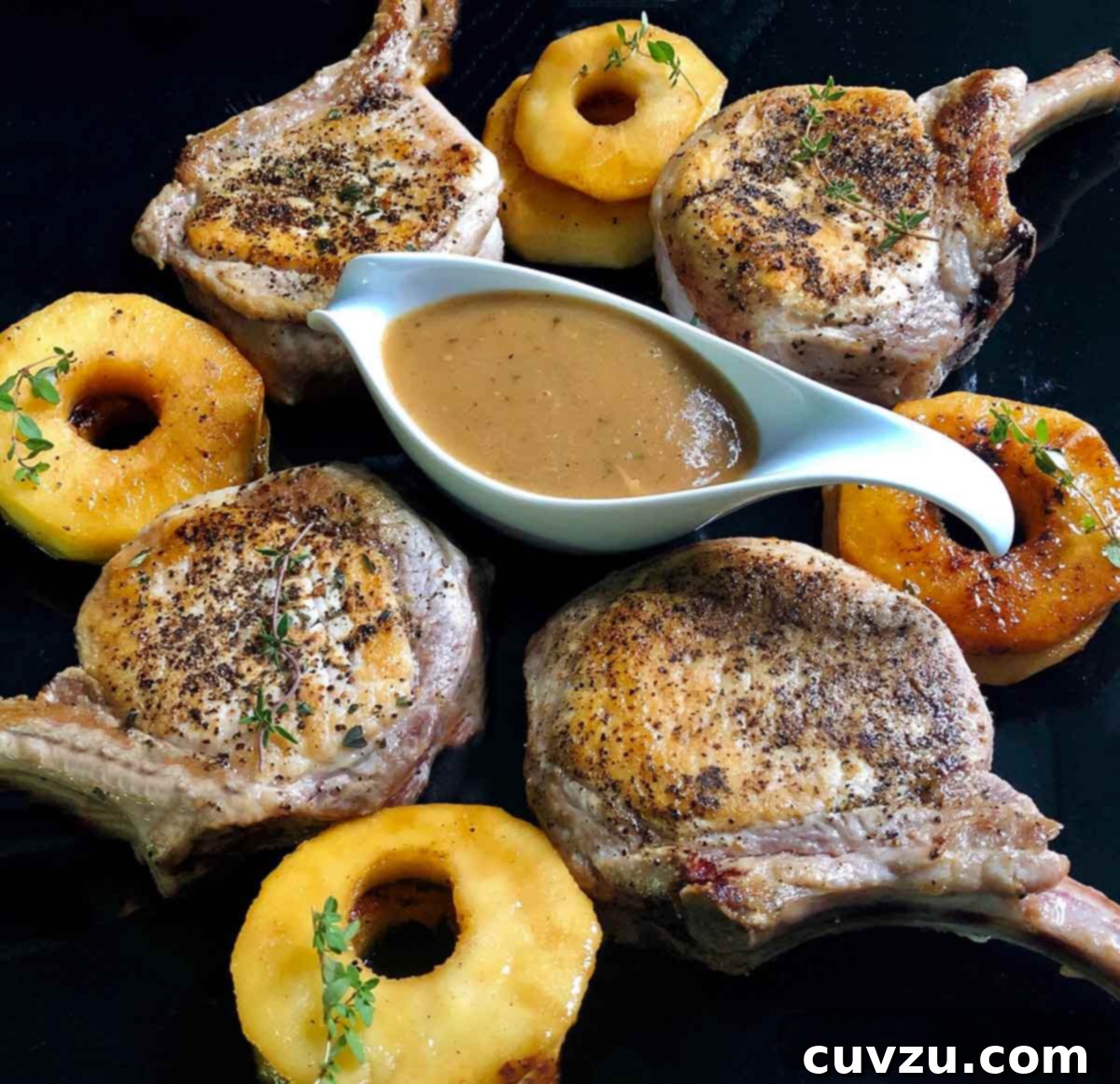 Normandy Pork Chops with Apples and Calvados 5 Four French-style pork chops with apples and calvados sauce in a gravy boat in the center.