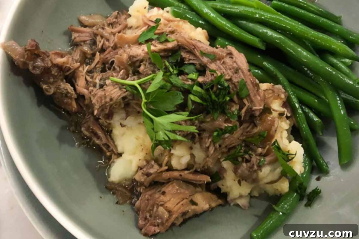 Succulent Wine-Braised Pork Shoulder 5 Braised pork with red wine sauce, mashed potatoes, and green beans on a plate.