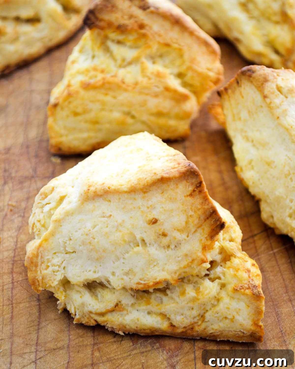 Eight Irresistible Homemade Biscuit Creations 3 Five irregular shaped cheddar biscuits with golden edges, on a wooden cutting board.