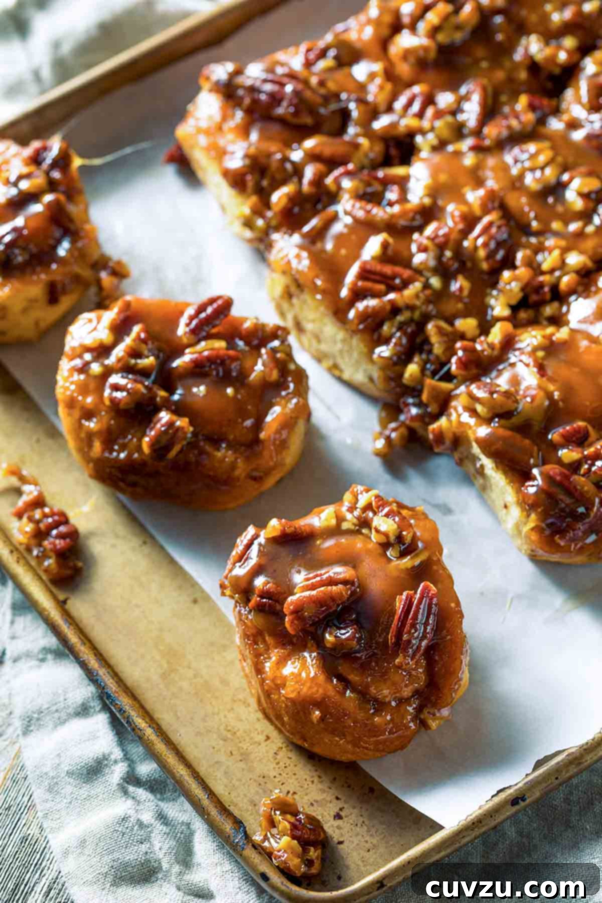 Eight Irresistible Homemade Biscuit Creations 9 A rimmed parchment-lined baking sheet filled with quick sticky biscuits that are coated in thick syrup and topped with pecans.