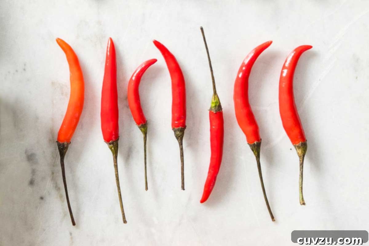 Fresh Chile Peppers: Decoding the Differences 8 Seven small, slender, bright red and green Thai chile peppers, indicating their intense hot heat, often used in Asian cuisine.