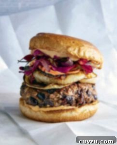 A black bean mushroom burger topped with onions, sauce, and purple leaves.