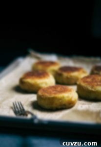 A sheet pan with six ground lamb and potato patties on parchment paper.