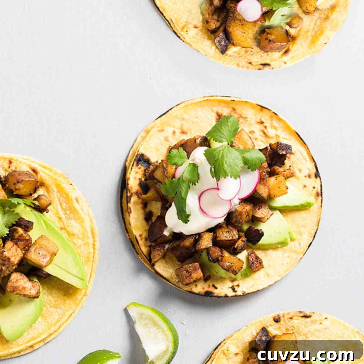 Four ancho pork and potato tacos topped with cubed pork and potatoes, sliced radish, sour cream, and cilantro.