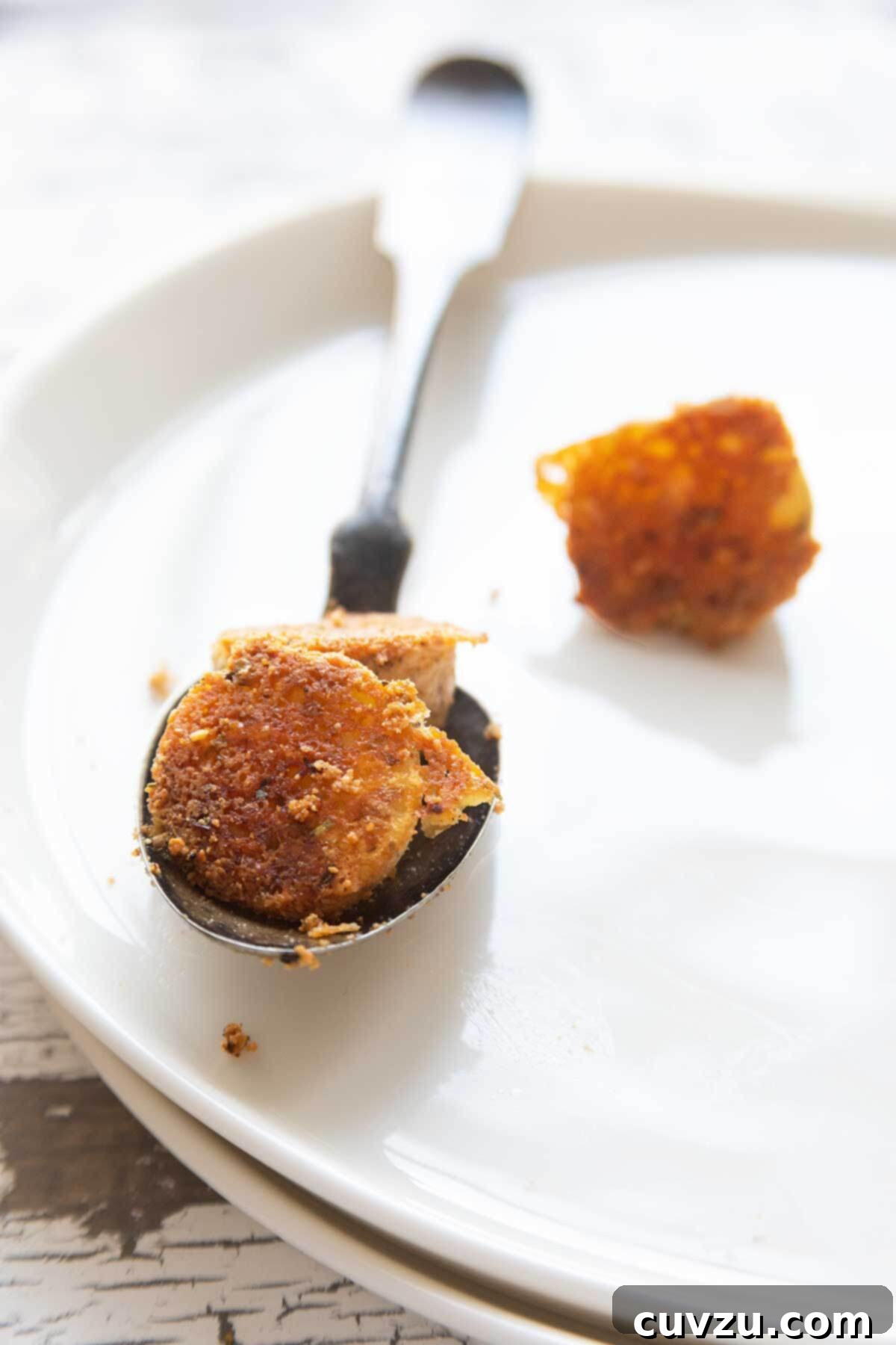 Savory Golden Parmesan Potato Bites 3 Crispy Parmesan potatoes on a spoon on a white plate.