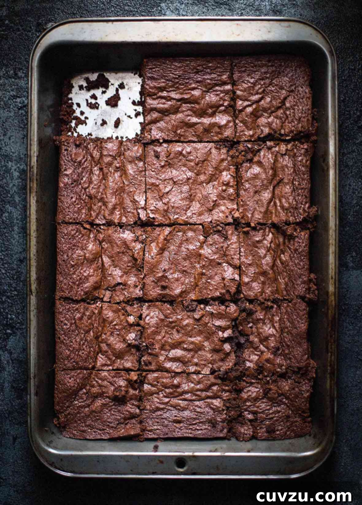 A metal baking pan of gluten free brownies with one piece missing