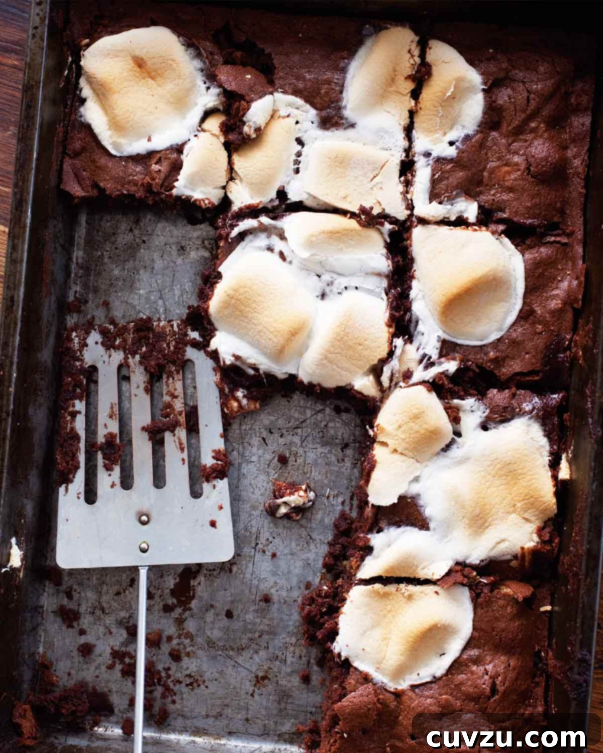 A tray of s'mores brownies with a spatula resting inside and several brownies missing.