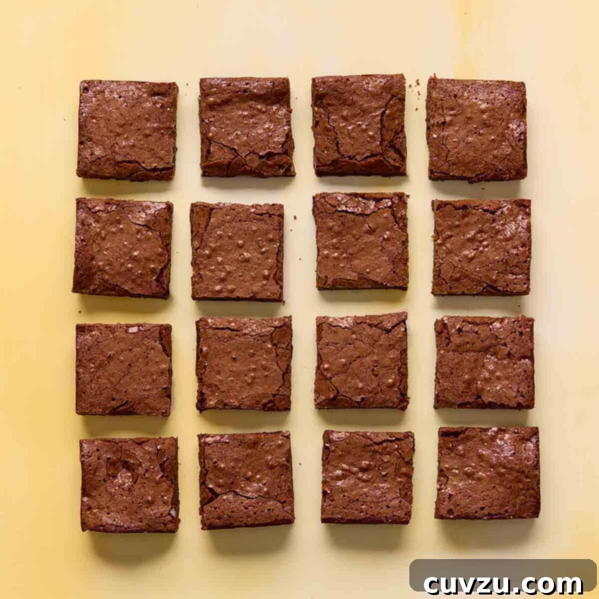 Sixteen square brownies on a yellow background.