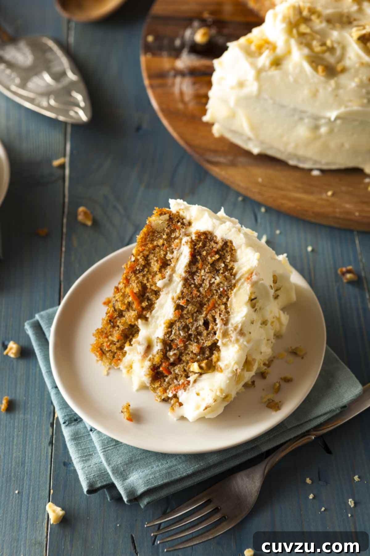 A slice of classic carrot cake—two moist carrot cake layers filled and frosted with luscious cream cheese frosting, topped with crushed walnuts.
