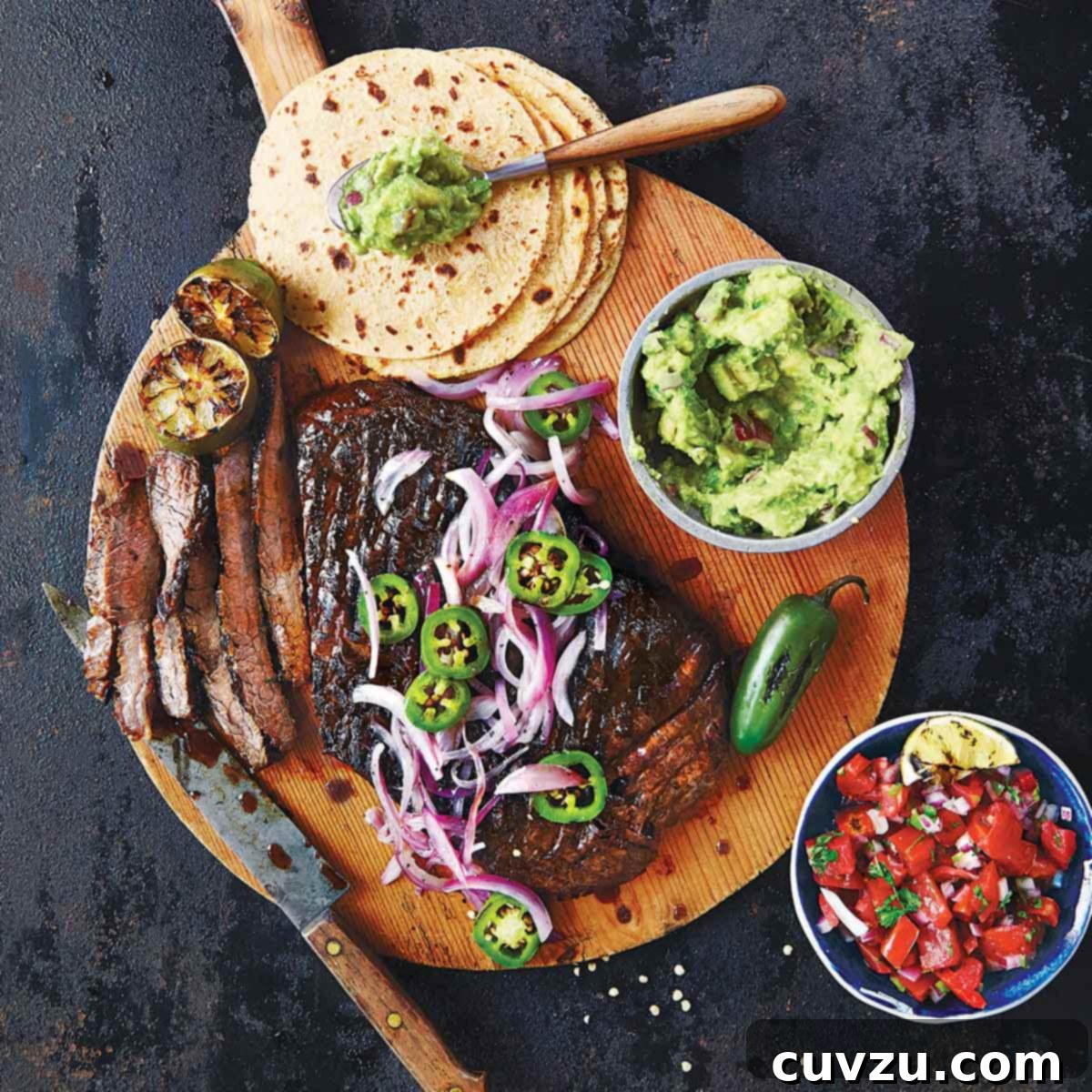 The makings of beef fajitas on a wooden board - warm tortillas, perfectly cooked steak, fresh guacamole, and zesty salsa.