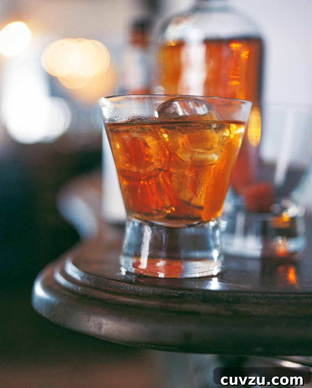A highball glass filled with a classic old-fashioned cocktail and large ice cubes, ready to be enjoyed.