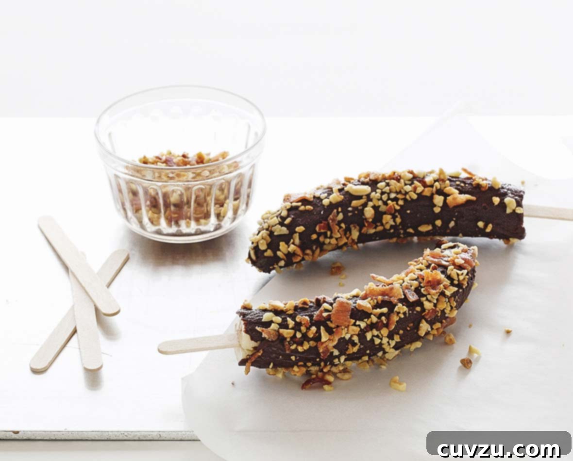 Two frozen chocolate-covered bananas on sticks with a dish of crushed peanuts, a primal indulgence for Scorpio.