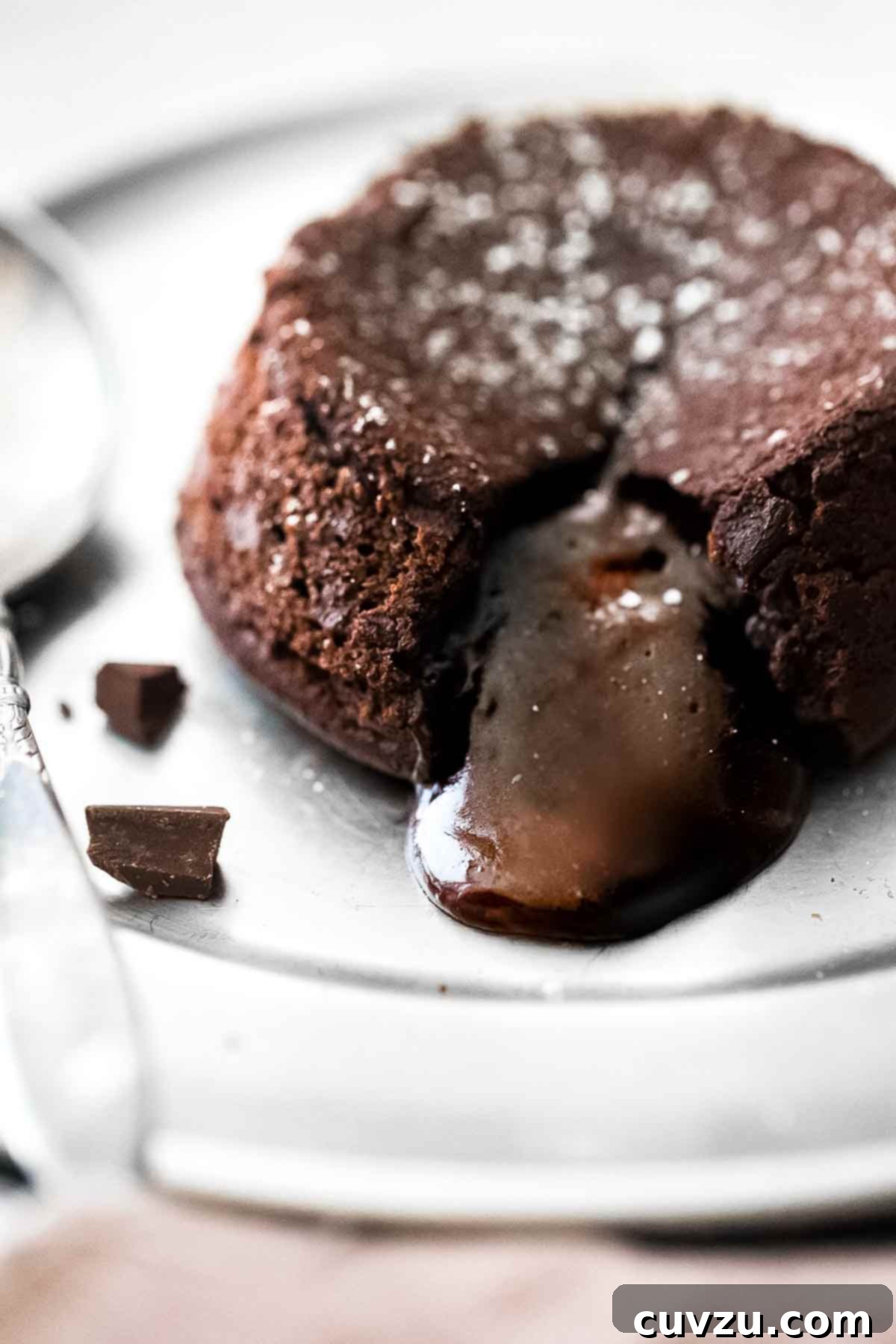 A molten chocolate cake on a plate with the filling oozing out and a few pieces of dark chocolate on the side, representing sophisticated indulgence for Capricorn.